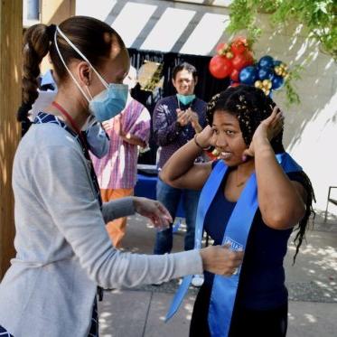 girl helping other girl to wear stole