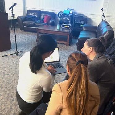 group of people discussing and one lady is showing something on the laptop