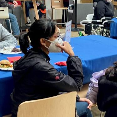 two women wearing masks sitting opposite to each other on a table