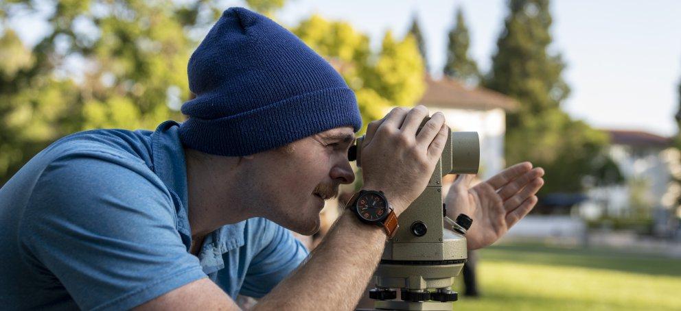 Male student looking through survey tool on lawn of SMC campus